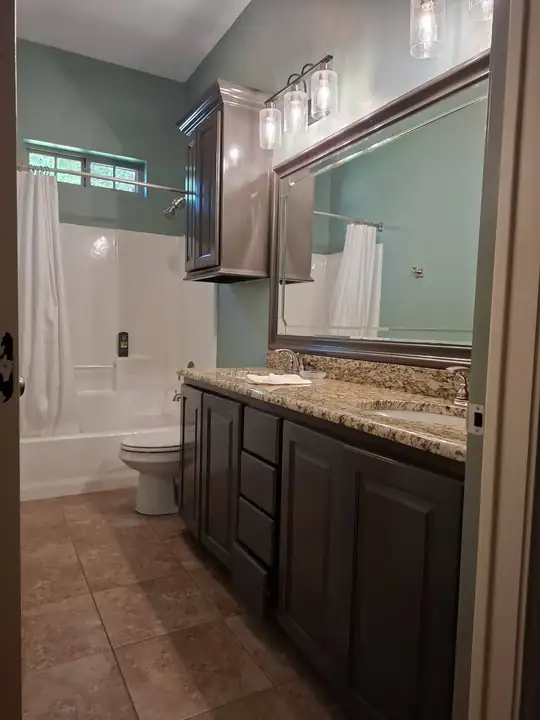 Long dark vanity with granite top, framed mirror and tub