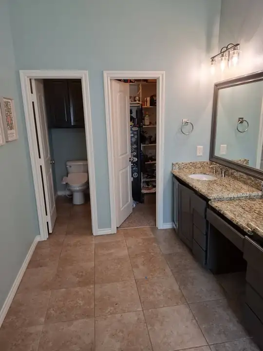 Looking across the finished room toward the doors to the water closet and a closet, over a tile floor