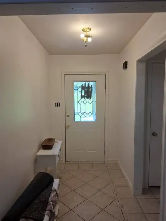 The same entry hall after: walls painted cream around the leaded-glass door