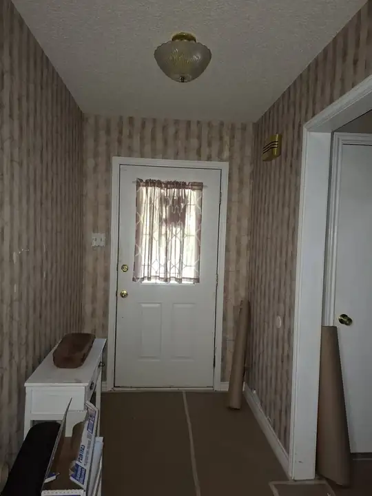 Entry hall before: striped wallpaper and paper on the floor
