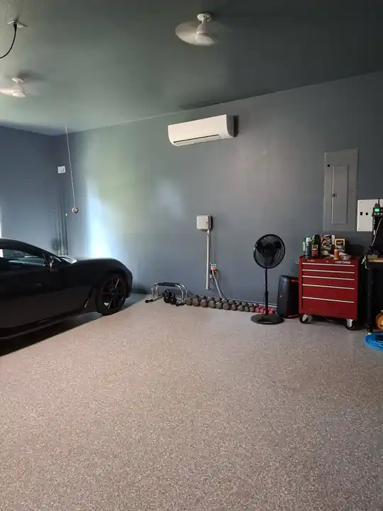 Finished garage with slate walls, a mini-split, a black car and a tool chest