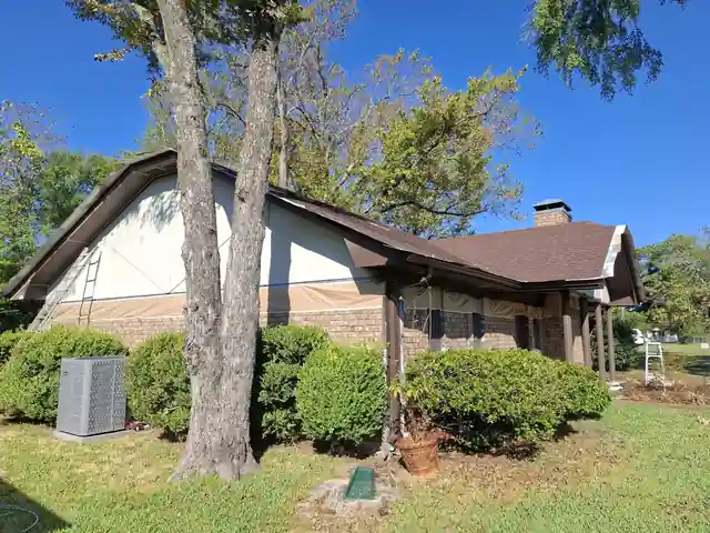 Side gable with a ladder against the brick, an AC unit and shrubs