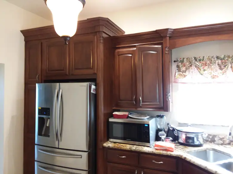 Cherry-stained kitchen cabinets beside a stainless refrigerator