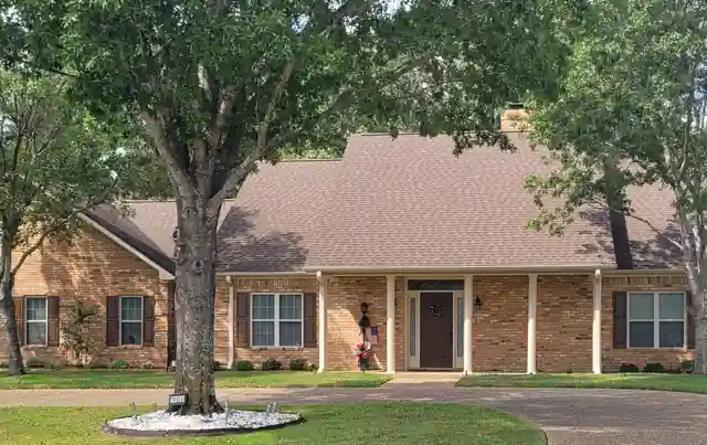 Brick ranch house with white columns and black shutters under an oak, painted by Reeves Painting