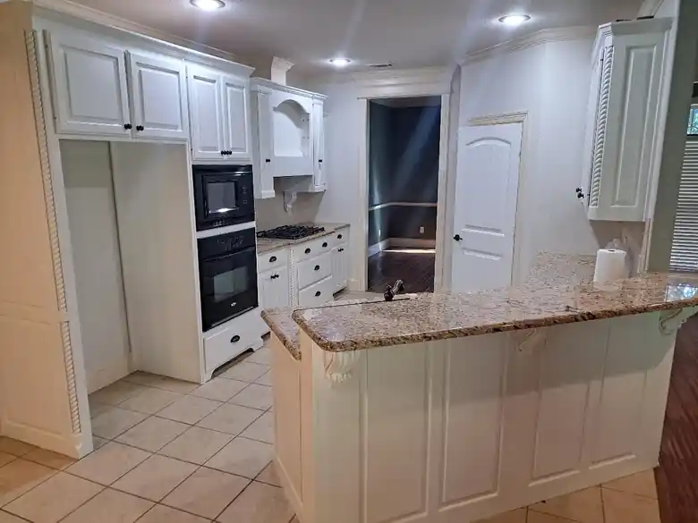 White-painted kitchen with granite counters and double ovens