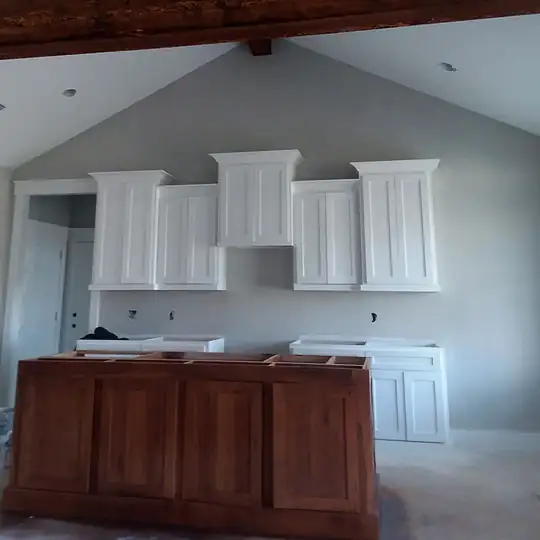 Kitchen with white upper cabinets and a walnut island under a vaulted ceiling