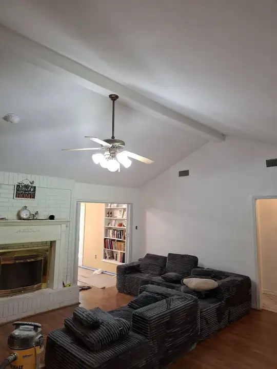 The same vaulted living room finished: smooth ceiling, white beam, ceiling fan