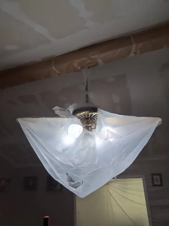 A ceiling light wrapped in a plastic bag so no paint or mud reaches it