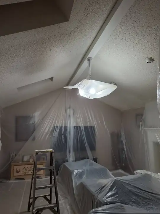 The same vaulted room with a ladder and a sheeted sofa