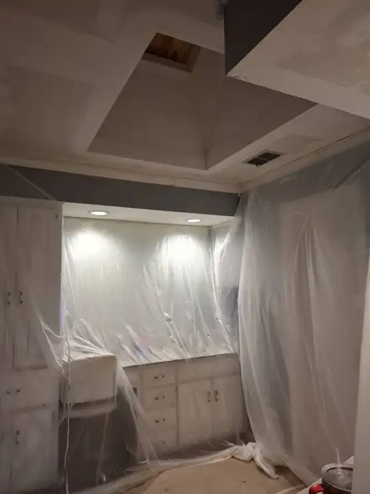 Bathroom vanity fully wrapped in poly under a coffered ceiling